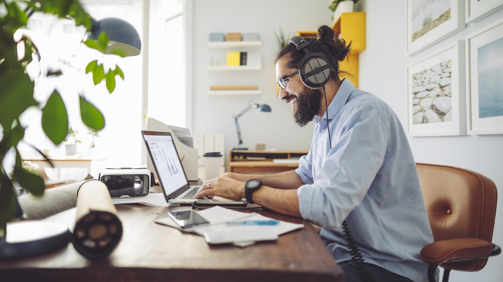 Een man met behulp van een laptop computer zittend op de top van een bureau