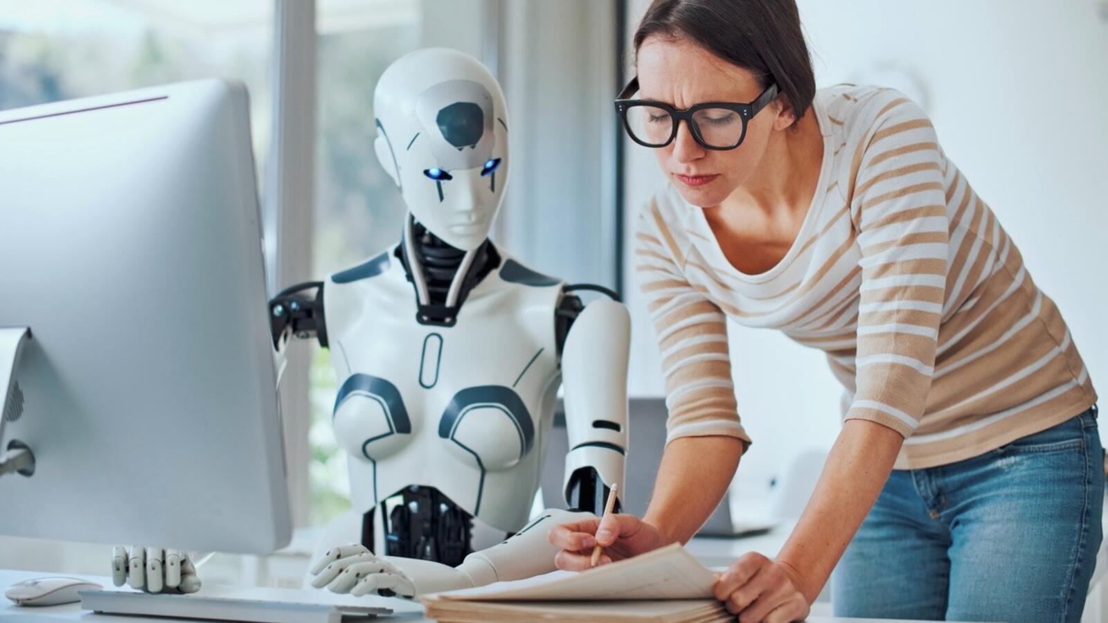 een persoon en een robot die aan een bureau zitten